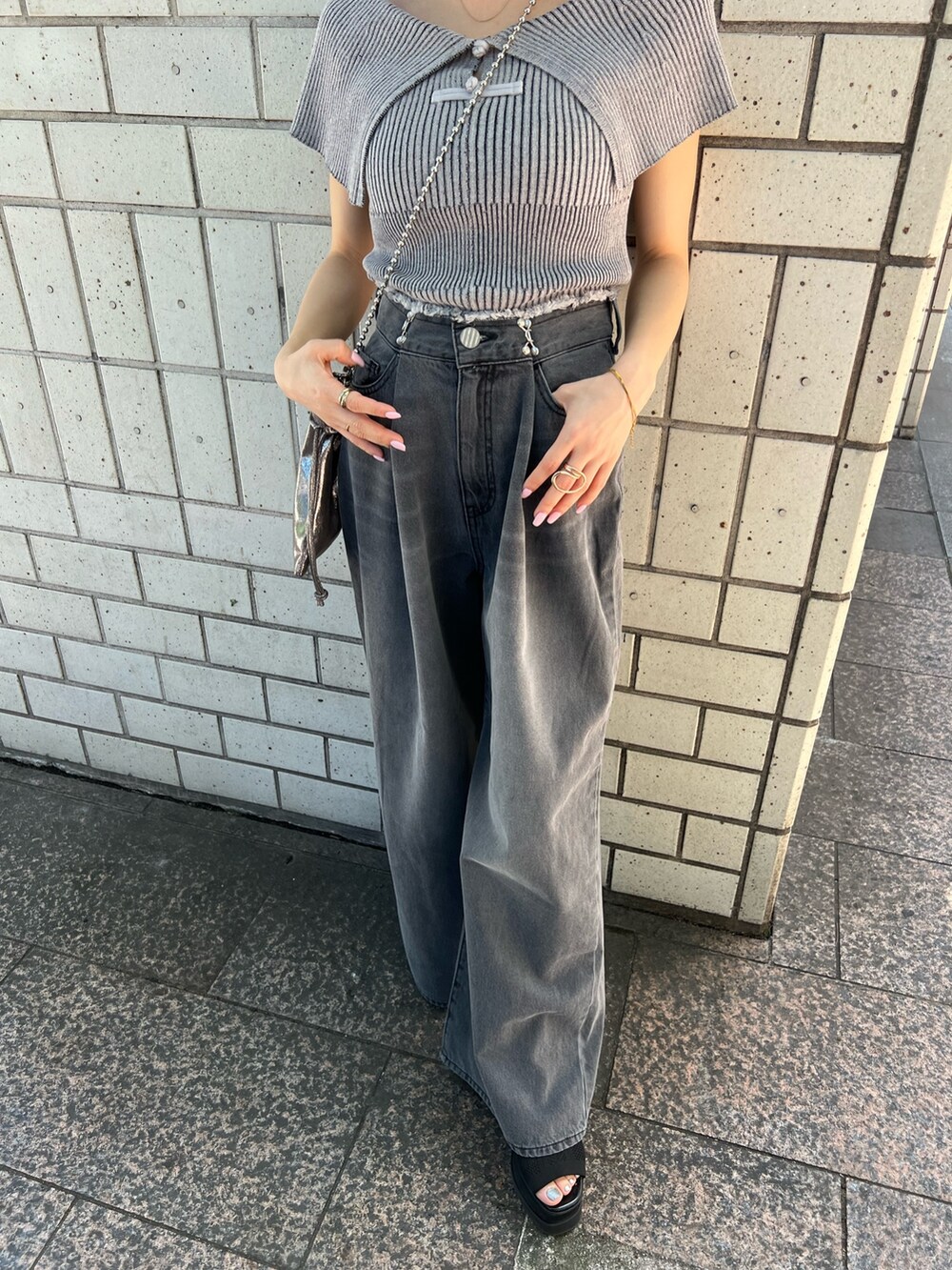 グレー系のニット/セーター、ブラック系のデニムパンツ、ブラック系のサンダルを着用したレディースの春コーディネートの7枚目の写真