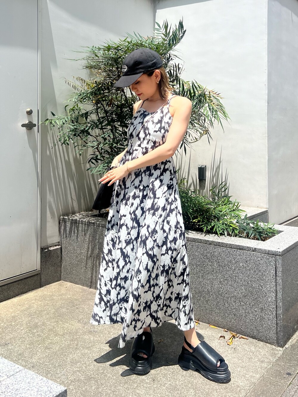 ホワイト系のワンピース、ブラック系のショルダーバッグ、ブラック系のサンダルを着用したレディースの夏コーディネートの2枚目の写真