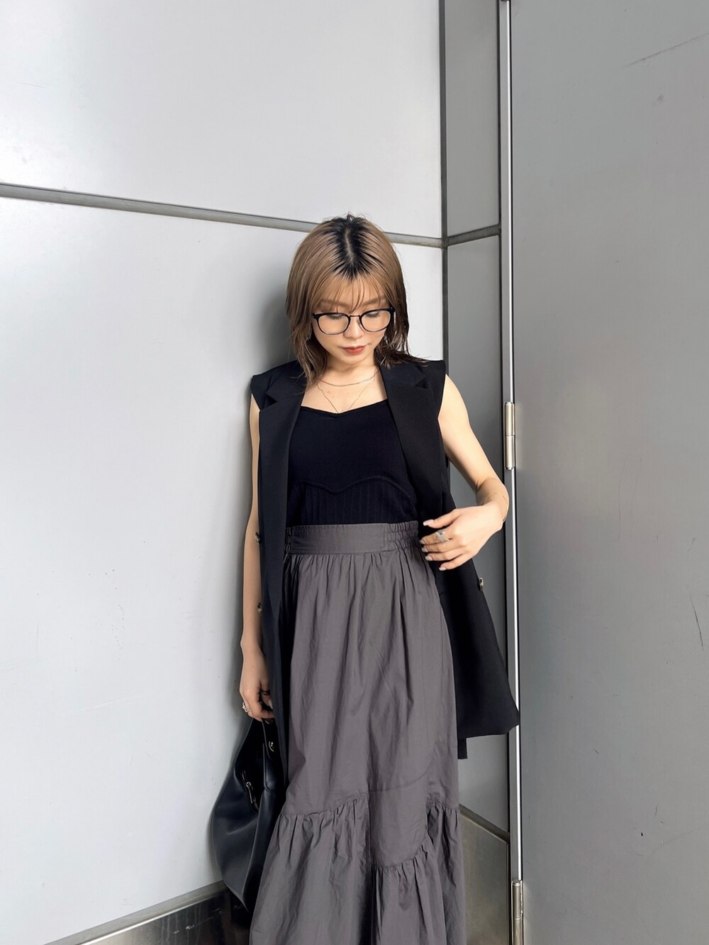 ブラック系のベスト、ブラック系のニット/セーター、グレー系のスカートを着用したレディースの夏コーディネートの6枚目の写真