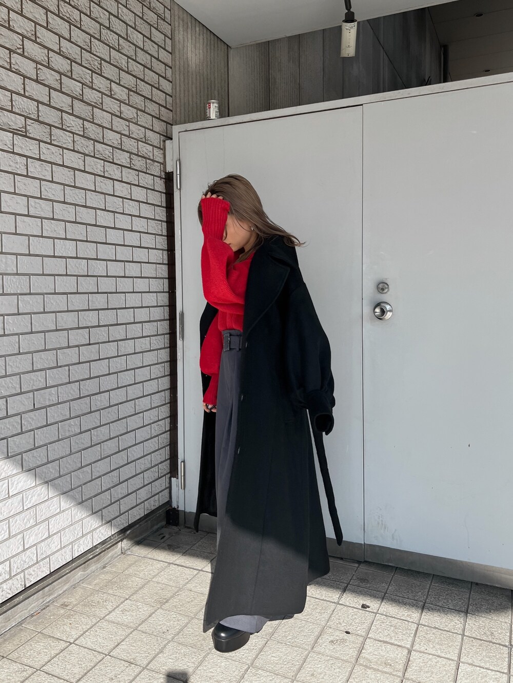 レッド系のニット/セーター、ブラック系のダウンジャケット/コート、ブラック系のブーツを着用したレディースの秋コーディネートの7枚目の写真