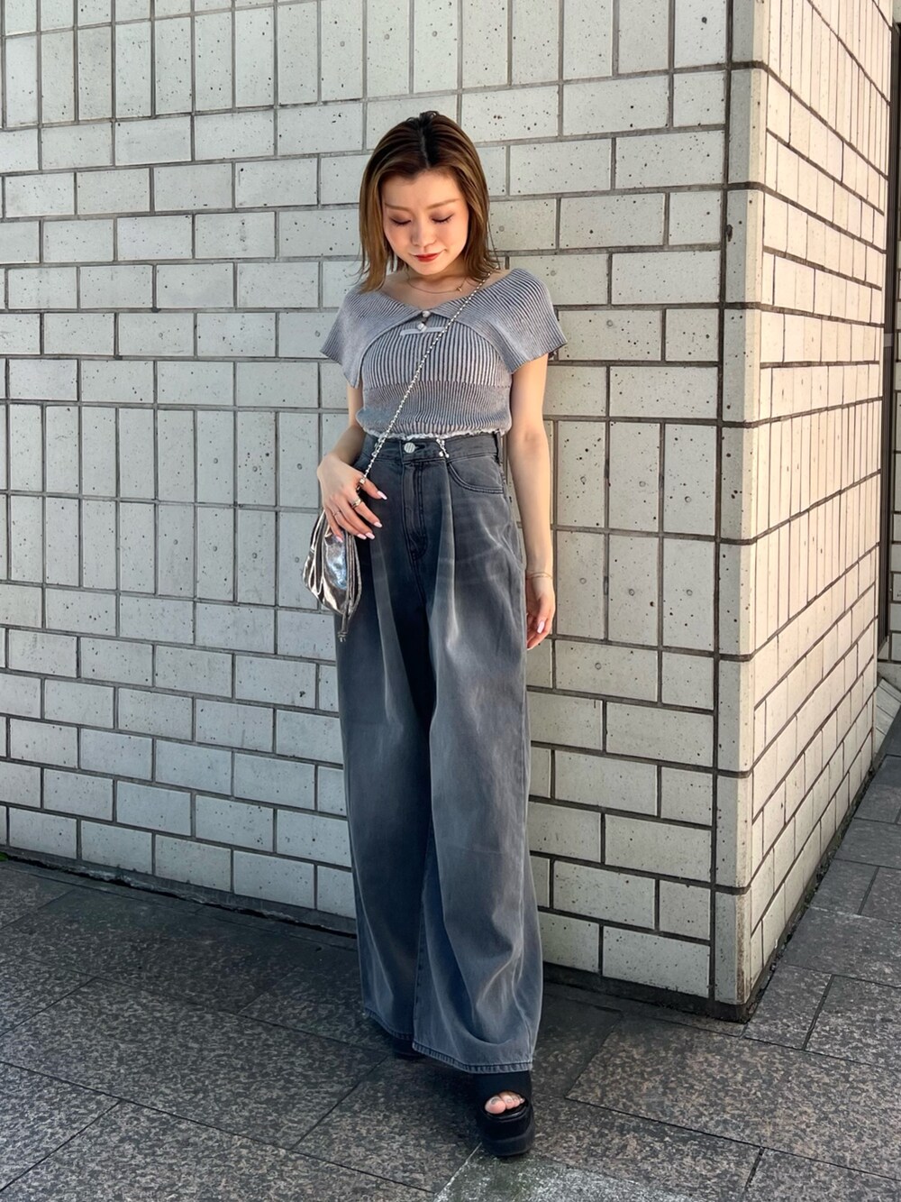 グレー系のニット/セーター、ブラック系のデニムパンツ、ブラック系のサンダルを着用したレディースの春コーディネートの4枚目の写真