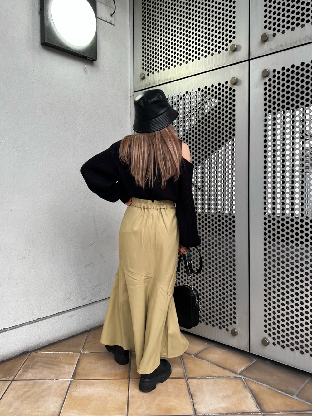 グリーン系のスカート、ブラック系のニット/セーター、ブラック系のショルダーバッグを着用したレディースの冬コーディネートの3枚目の写真