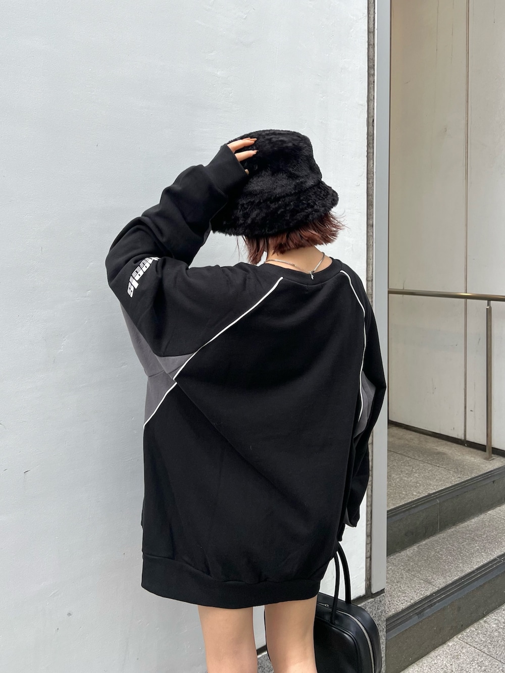 ブラック系のスウェット、ブラック系のブーツ、ブラック系のハットを着用したレディースの秋コーディネートの6枚目の写真