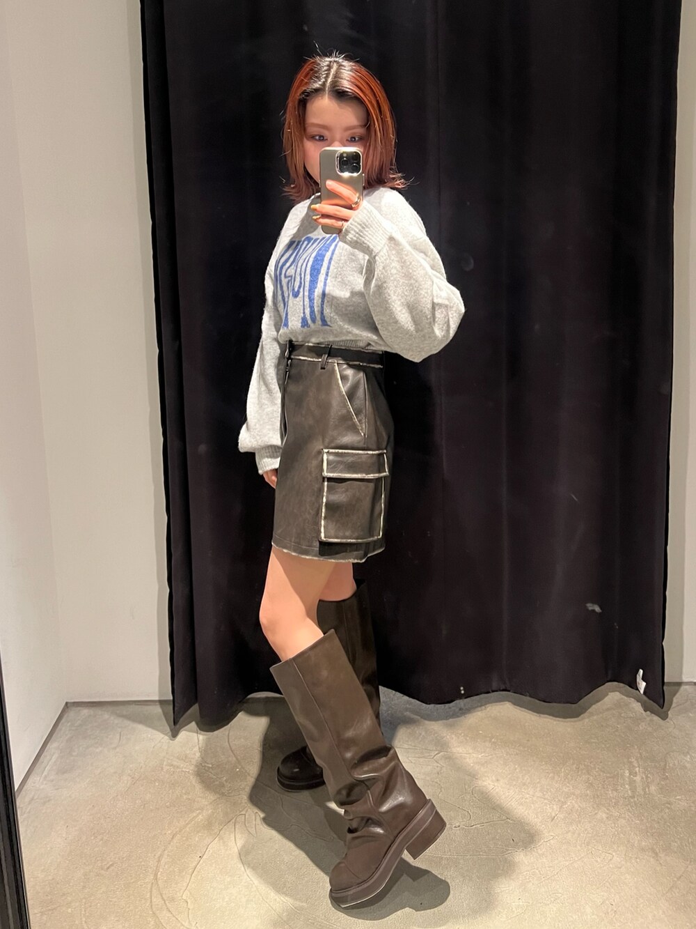 グレー系のニット/セーター、ブラウン系のブーツ、ブラウン系のスカートを着用したレディースの冬コーディネートの2枚目の写真