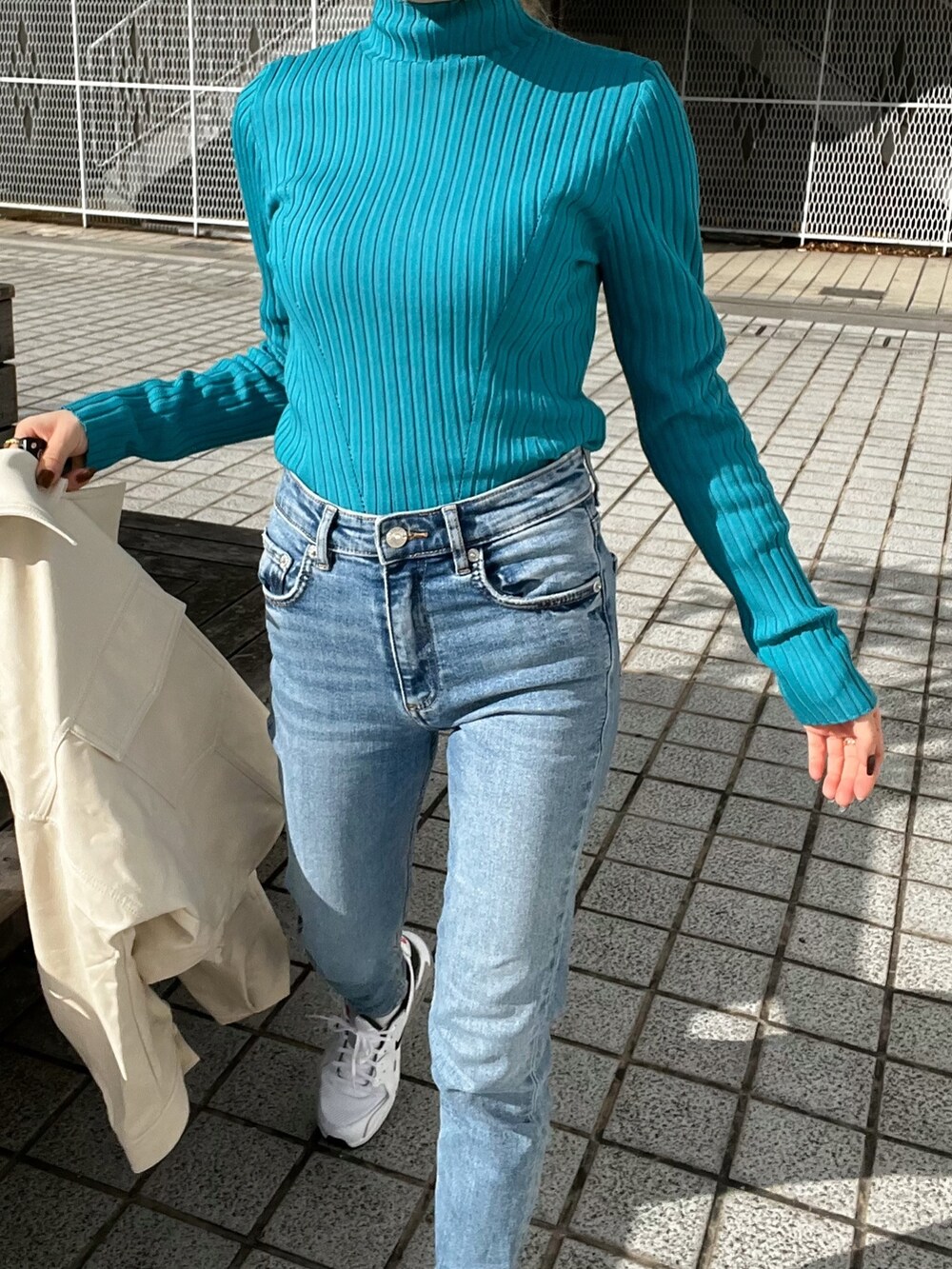 ホワイト系のライダースジャケット、ブルー系のニット/セーター、ブラック系のハンドバッグを着用したレディースの冬コーディネートの9枚目の写真