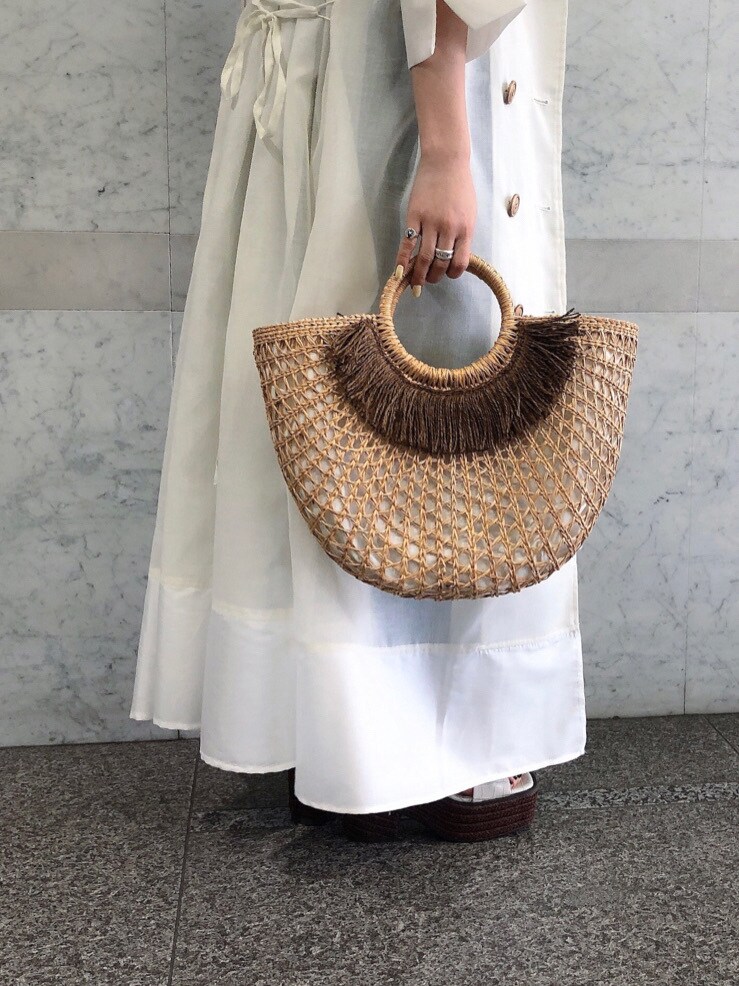 ホワイト系のキャミソール、ベージュ系のかごバッグ、ブルー系のデニムパンツを着用したレディースの春コーディネートの5枚目の写真