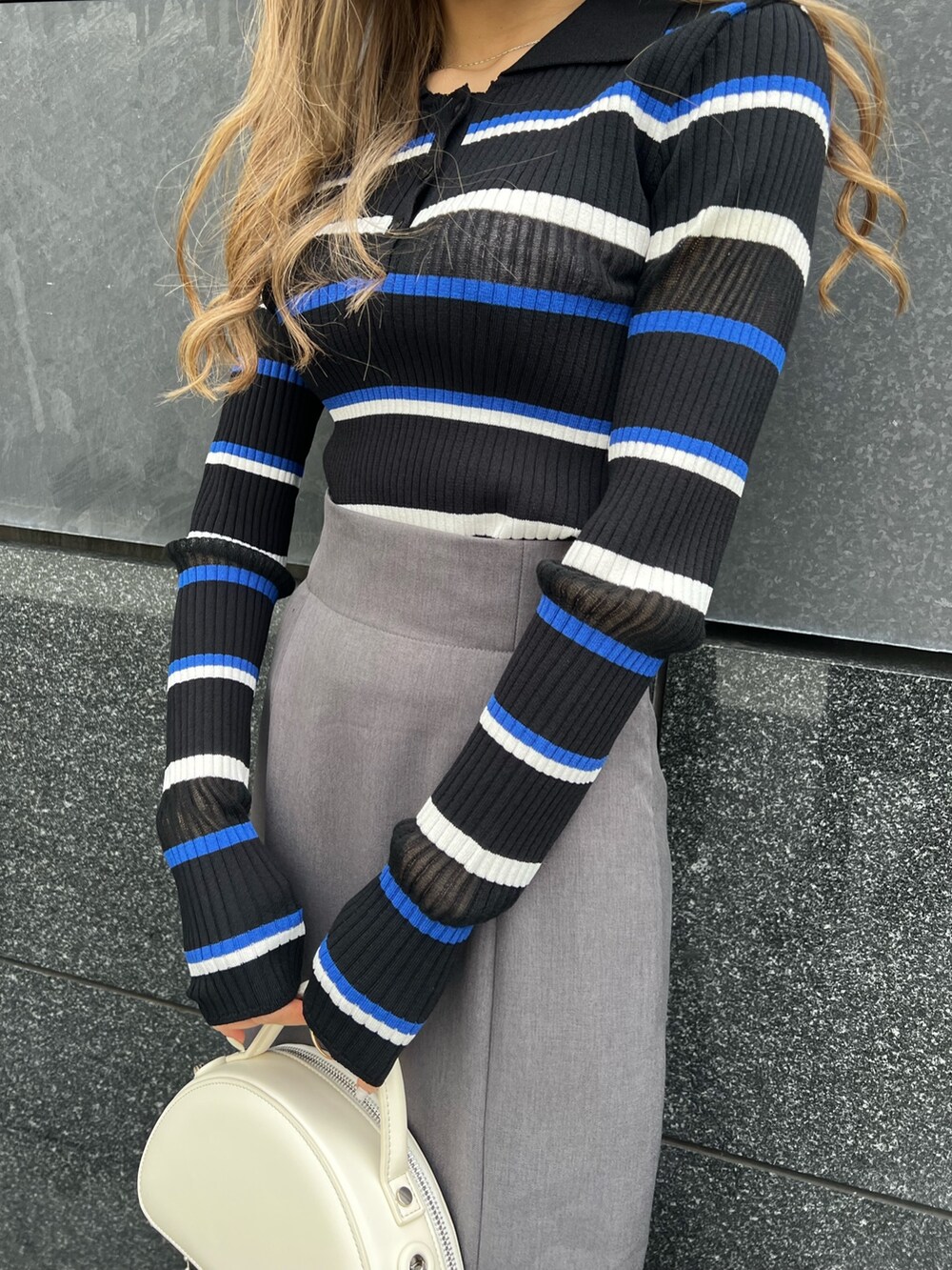 ブルー系のポロシャツ、グレー系のスカート、ブラック系のブーツを着用したレディースの春コーディネートの6枚目の写真