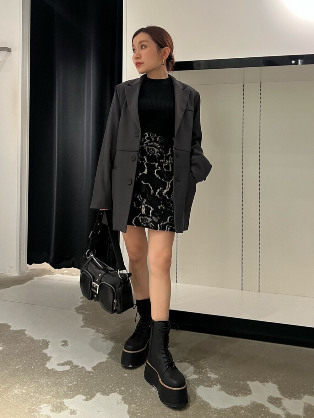 ブラック系のハンドバッグ、ブラウン系のブーツ、ブラック系のニット/セーターを着用したレディースの秋コーディネートの4枚目の写真