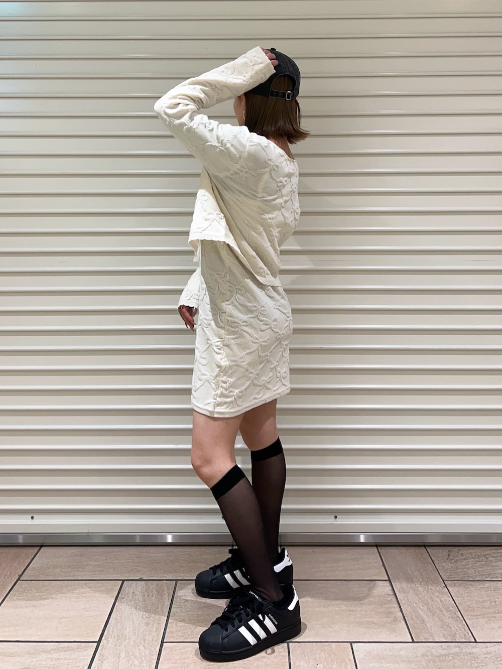 ホワイト系のワンピース、ホワイト系のカーディガン/ボレロ、ブラック系のキャップを着用したレディースの冬コーディネートの2枚目の写真