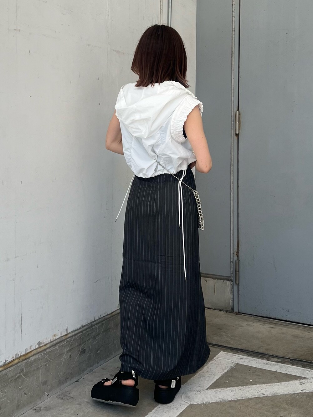 ホワイト系のベスト、ブラック系のタンクトップ、グレー系のスカートを着用したレディースの春コーディネートの3枚目の写真