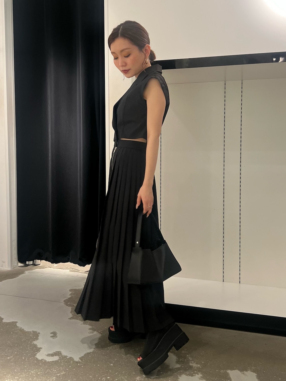 ブラック系のワンピース、ブラック系のサンダル、ブラック系のハンドバッグを着用したレディースの夏コーディネートの2枚目の写真