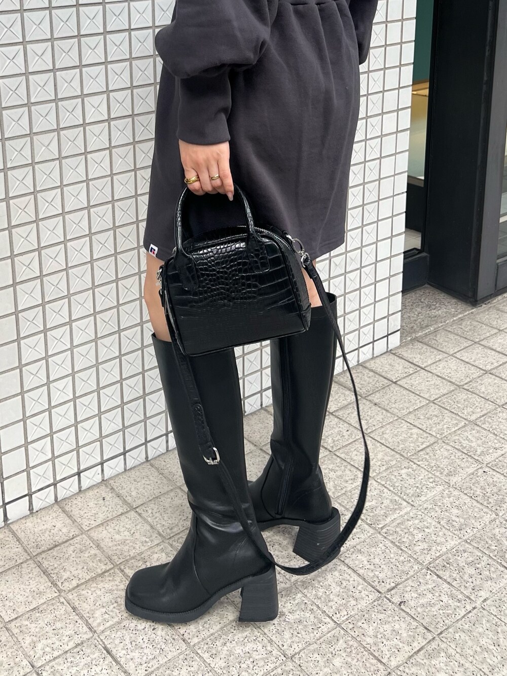 グレー系のワンピース、ブラック系のブーツ、ブラック系のボストンバッグを着用したレディースの夏コーディネートの7枚目の写真