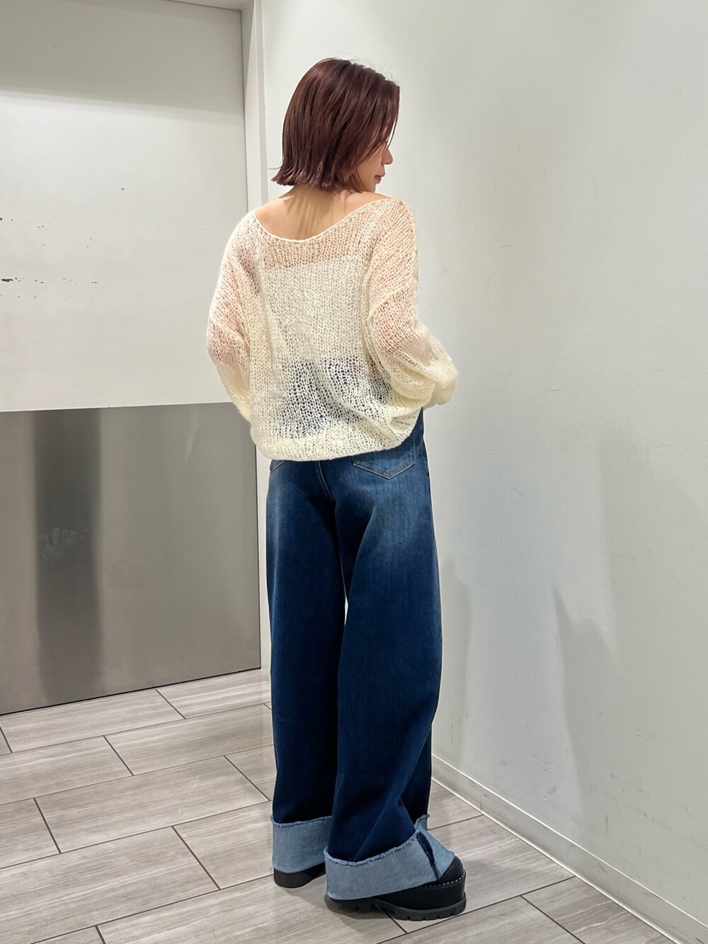 ブルー系のデニムパンツ、ホワイト系のニット/セーターを着用したレディースの秋コーディネートの2枚目の写真