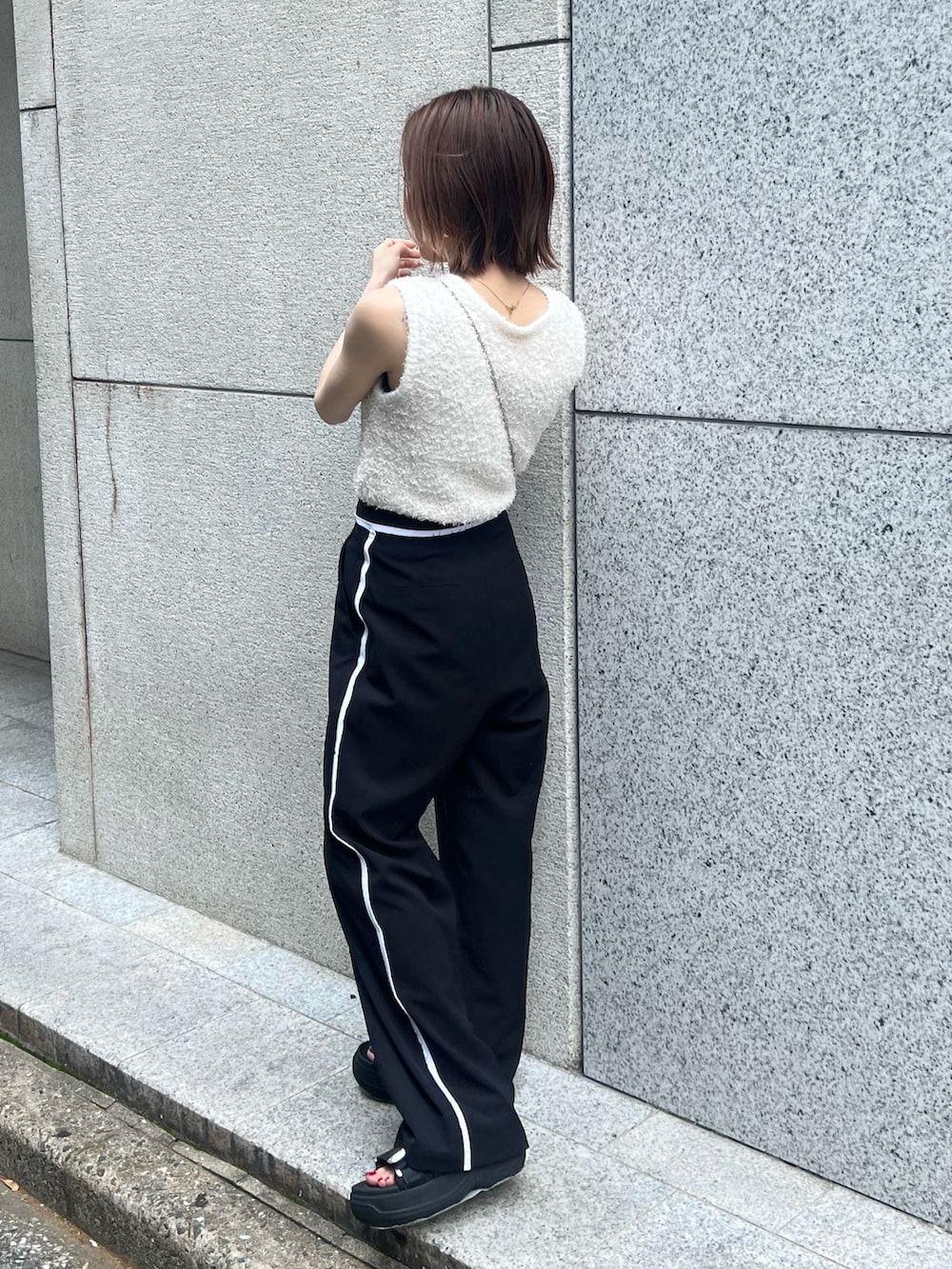 ホワイト系のニット/セーター、ブラック系のその他パンツ、ゴールド系のショルダーバッグを着用したレディースの夏コーディネートの2枚目の写真