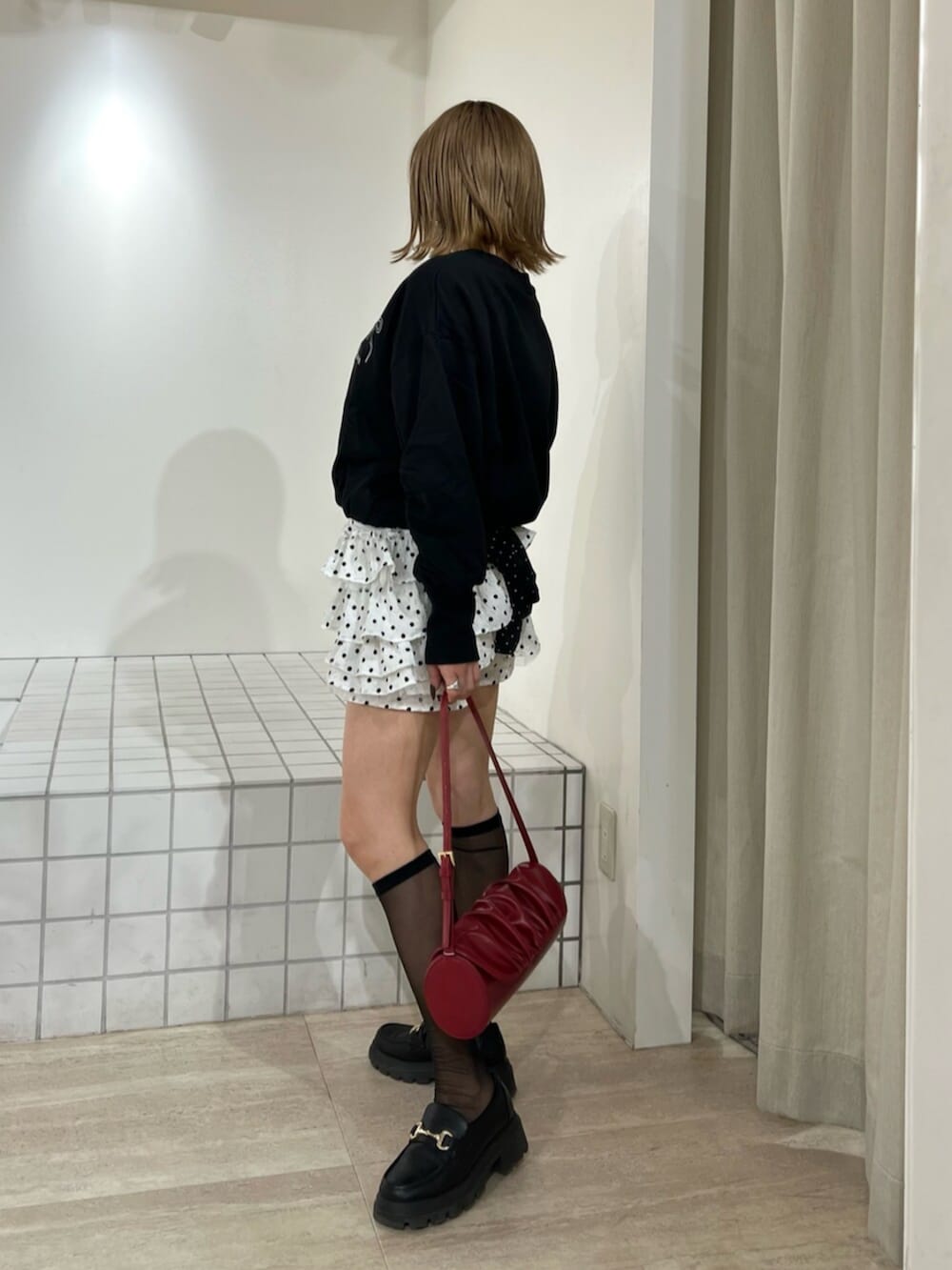 レッド系のハンドバッグ、ホワイト系のその他パンツ、ブラック系のスウェットを着用したレディースの冬コーディネートの2枚目の写真