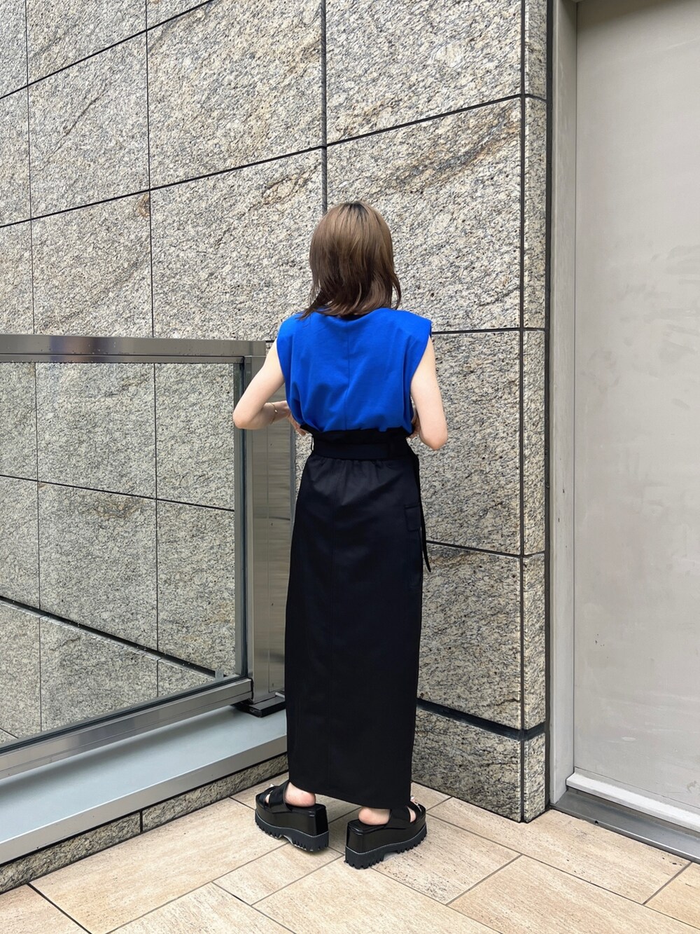 ブラック系のスカート、ブラック系のサンダル、ブルー系のTシャツ/カットソーを着用したレディースの夏コーディネートの3枚目の写真