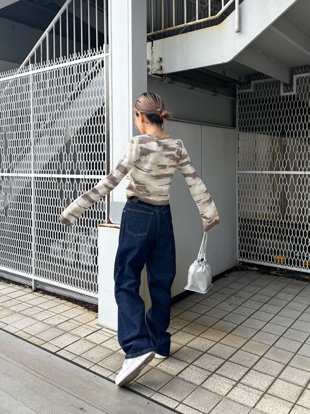 ブルー系のデニムパンツ、シルバー系のハンドバッグ、ベージュ系のカーディガン/ボレロを着用したレディースの冬コーディネートの2枚目の写真