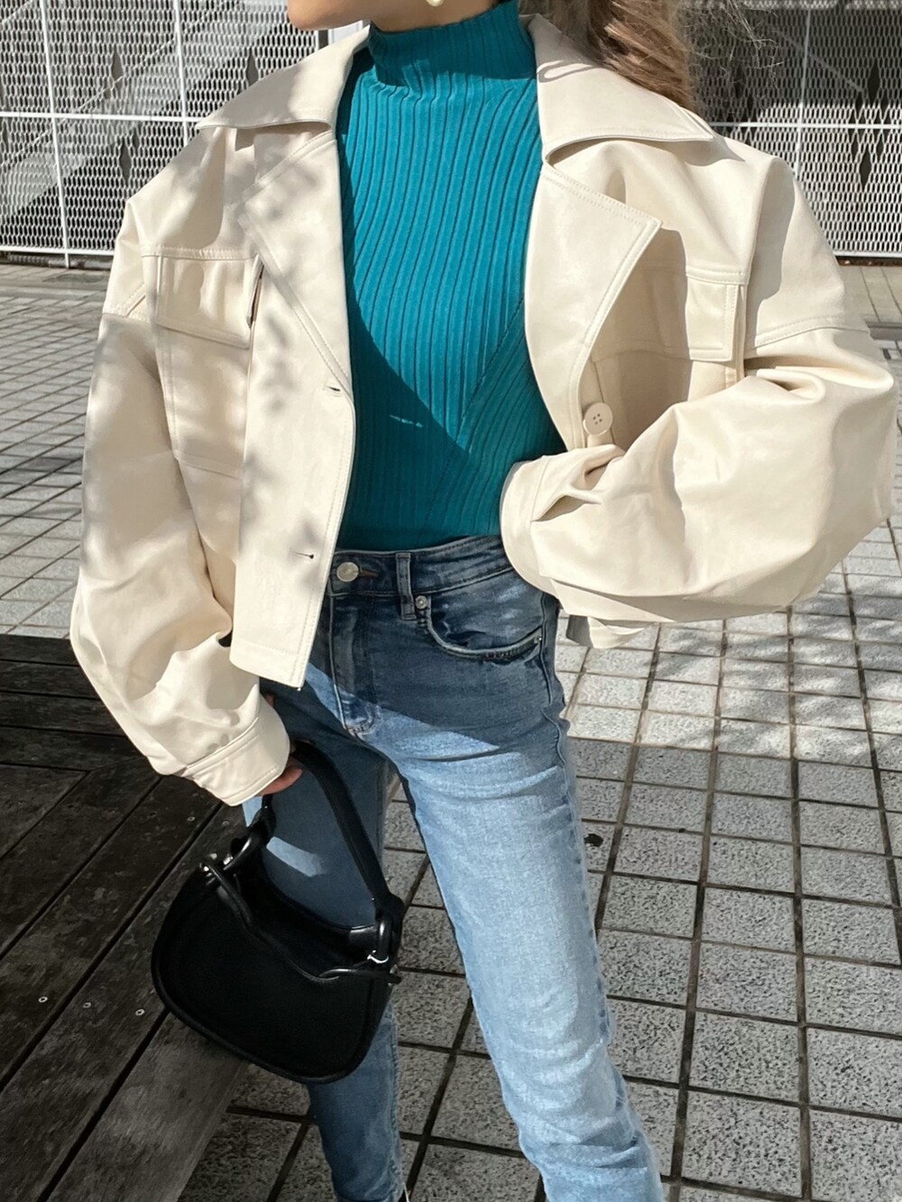 ホワイト系のライダースジャケット、ブルー系のニット/セーター、ブラック系のハンドバッグを着用したレディースの冬コーディネートの7枚目の写真