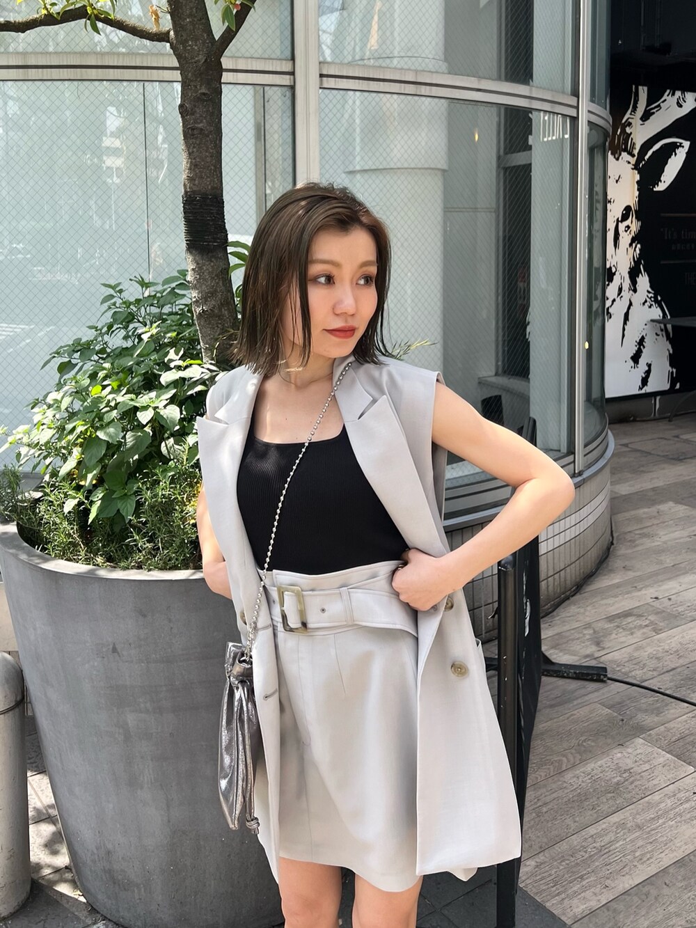 グレー系のベスト、ブラック系のブーツ、グレー系のスカートを着用したレディースの春コーディネートの4枚目の写真