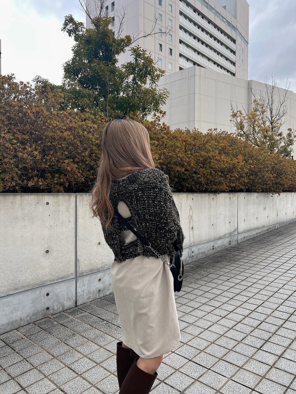 グリーン系のワンピース、ブラック系のショルダーバッグ、ブラウン系のブーツを着用したレディースの冬コーディネートの6枚目の写真