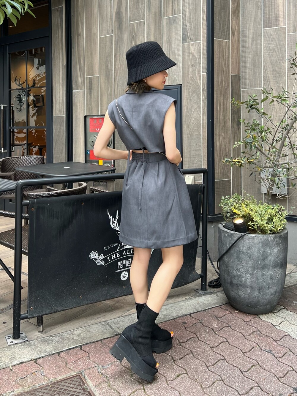 グレー系のワンピース、ブラック系のショルダーバッグ、ブラック系のブーツを着用したレディースの春コーディネートの3枚目の写真