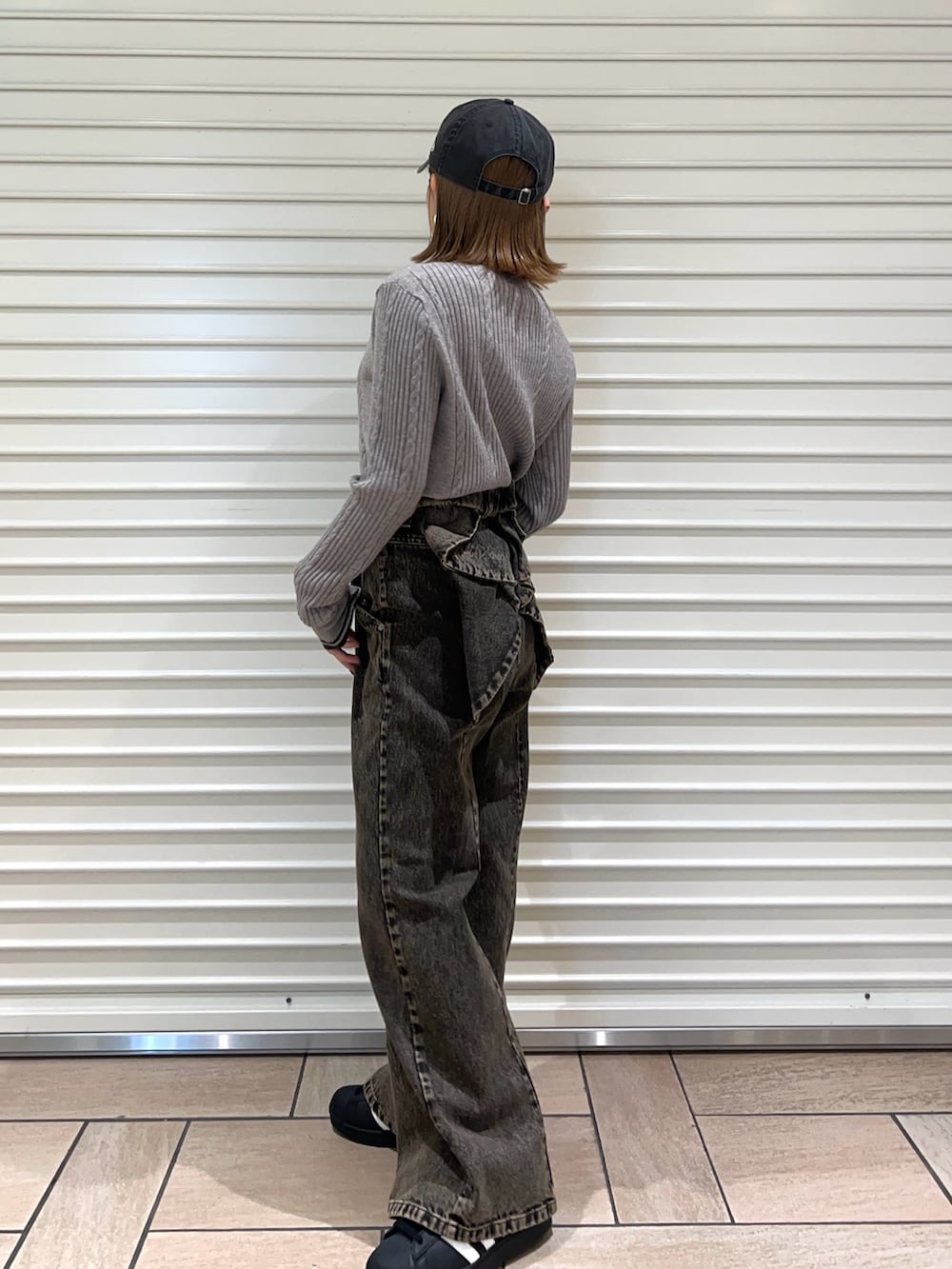 グレー系のニット/セーター、ブラック系のデニムパンツ、ブラック系のキャップを着用したレディースの冬コーディネートの2枚目の写真