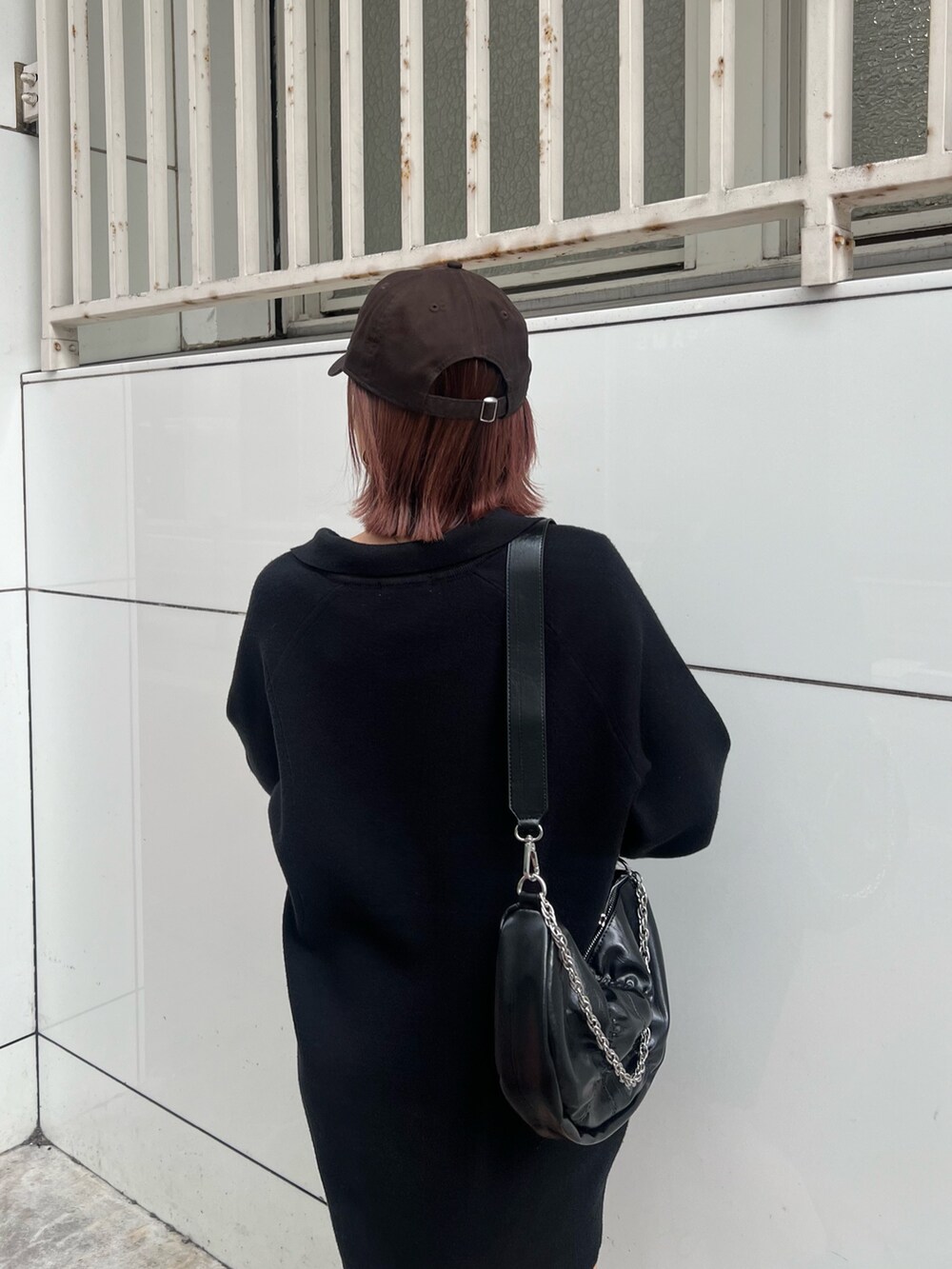 ブラック系のショルダーバッグ、ブラック系のブーツ、ブラック系のワンピースを着用したレディースの冬コーディネートの5枚目の写真