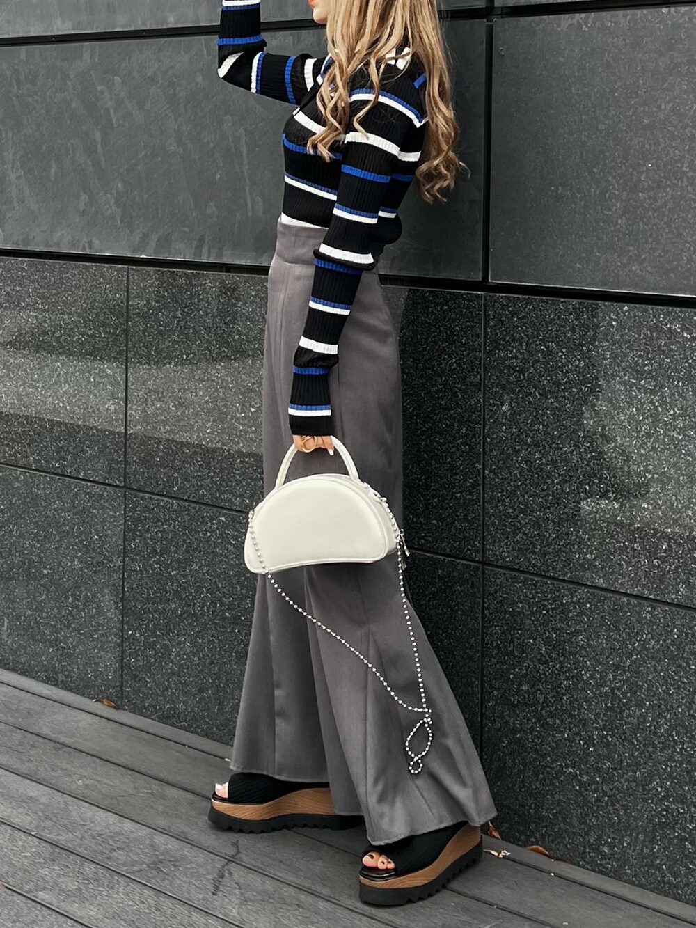 ブルー系のポロシャツ、グレー系のスカート、ブラック系のブーツを着用したレディースの春コーディネートの4枚目の写真