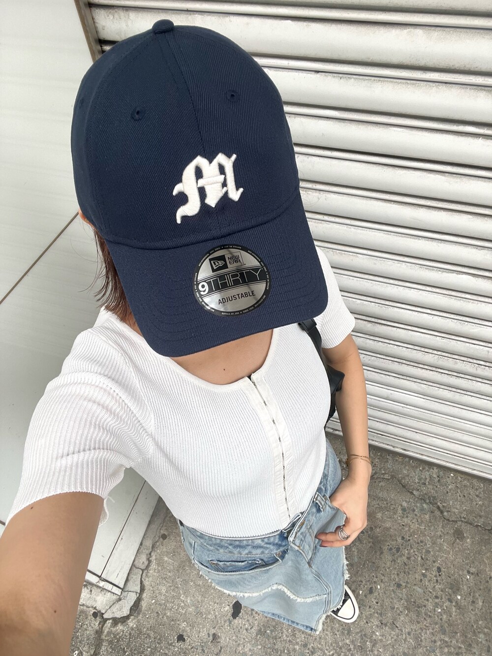 ホワイト系のニット/セーター、ブルー系のデニムスカート、ブラック系のハンドバッグを着用したレディースの夏コーディネートの9枚目の写真