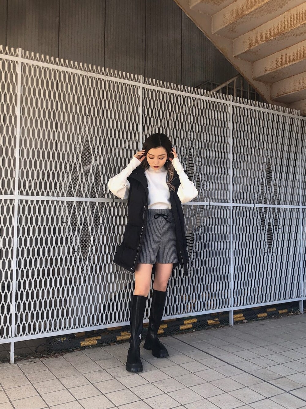 グレー系のその他パンツ、ブラック系のブーツ、ブラック系のダウンベストを着用したレディースの秋コーディネートの2枚目の写真