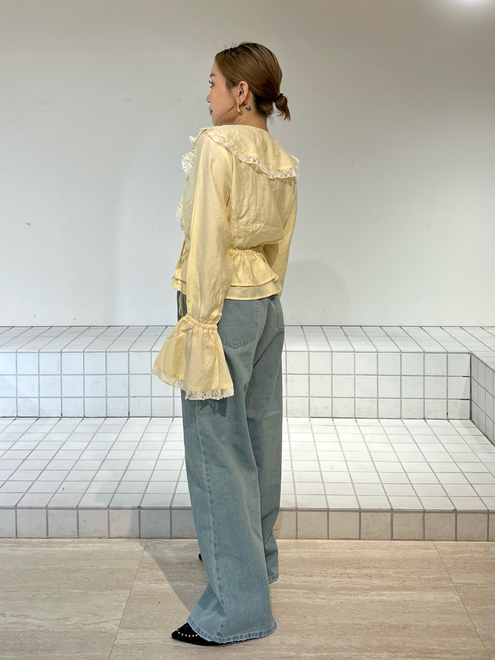 ブルー系のデニムパンツ、イエロー系のシャツ/ブラウス、ブラック系のサンダルを着用したレディースの春コーディネートの2枚目の写真