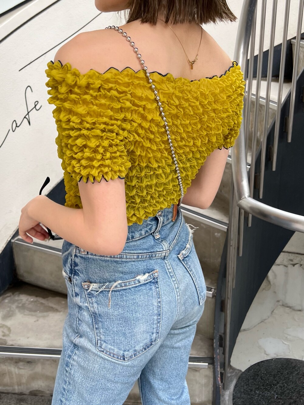 ブラック系のショルダーバッグ、イエロー系のシャツ/ブラウス、ブラック系のサングラスを着用したレディースの春コーディネートの7枚目の写真