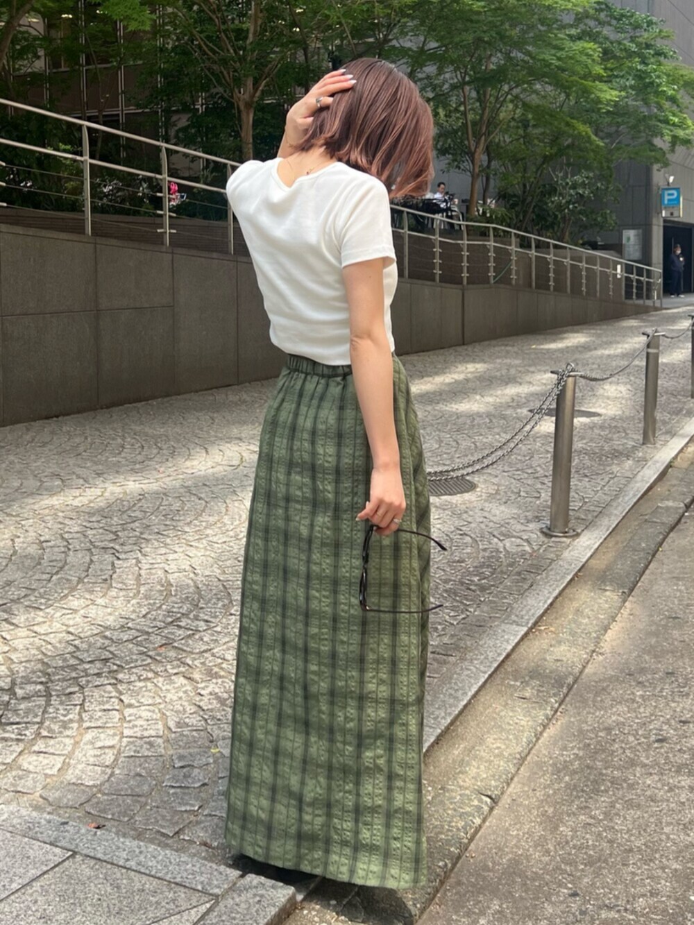 ブラック系のサンダル、ホワイト系のTシャツ/カットソー、グリーン系のスカートを着用したレディースの春コーディネートの2枚目の写真