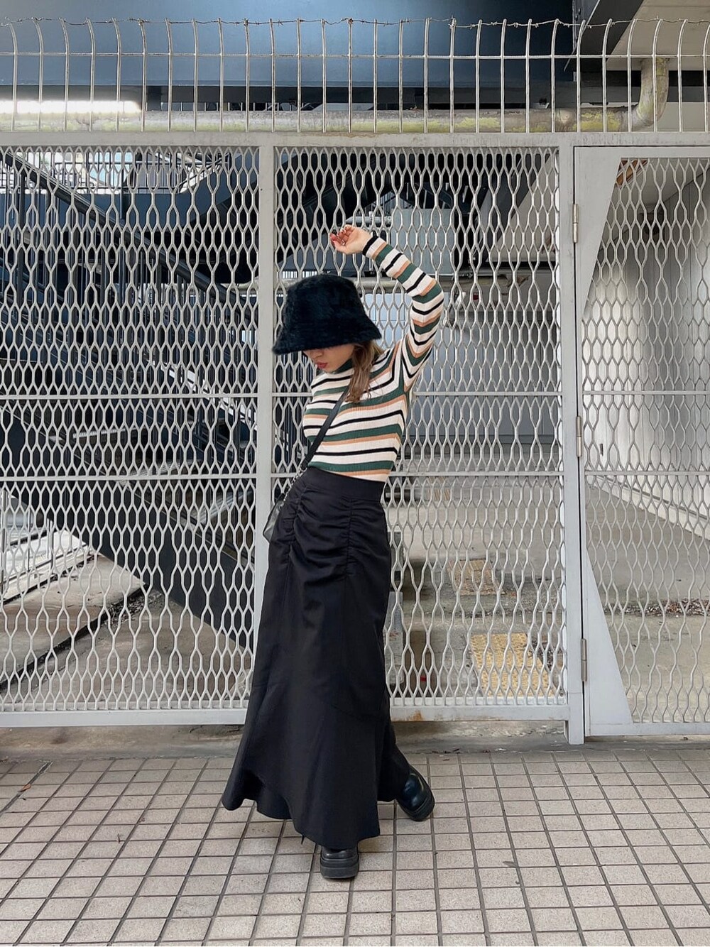 ブラック系のブーツ、ブラック系のショルダーバッグ、ブラック系のスカートを着用したレディースの秋コーディネートの4枚目の写真