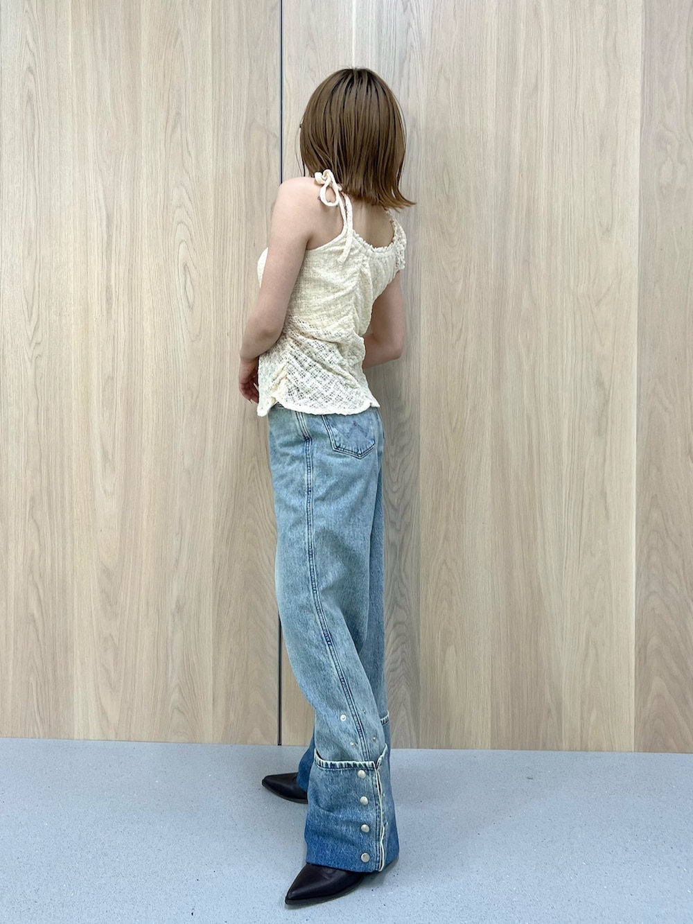 ホワイト系のタンクトップ、ブルー系のデニムパンツ、ブラウン系のブーツを着用したレディースの春コーディネートの2枚目の写真