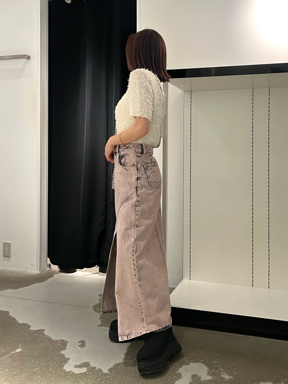 ホワイト系のニット/セーター、ピンク系のデニムスカート、ブラック系のブーツを着用したレディースの春コーディネートの3枚目の写真