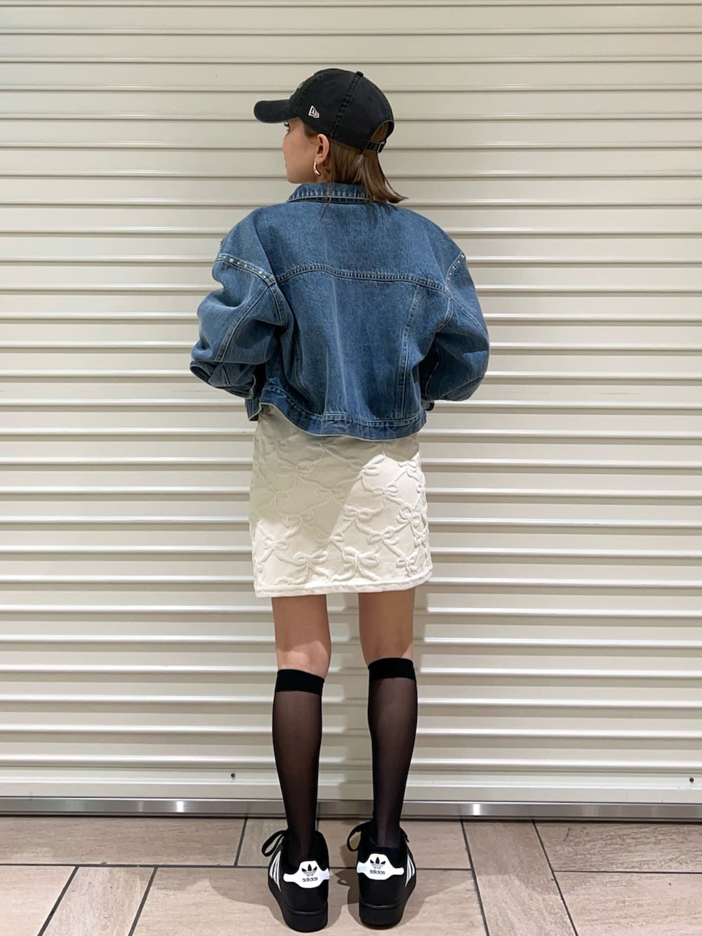 ブルー系のデニムジャケット、ホワイト系のワンピース、ブラック系のキャップを着用したレディースの春コーディネートの3枚目の写真