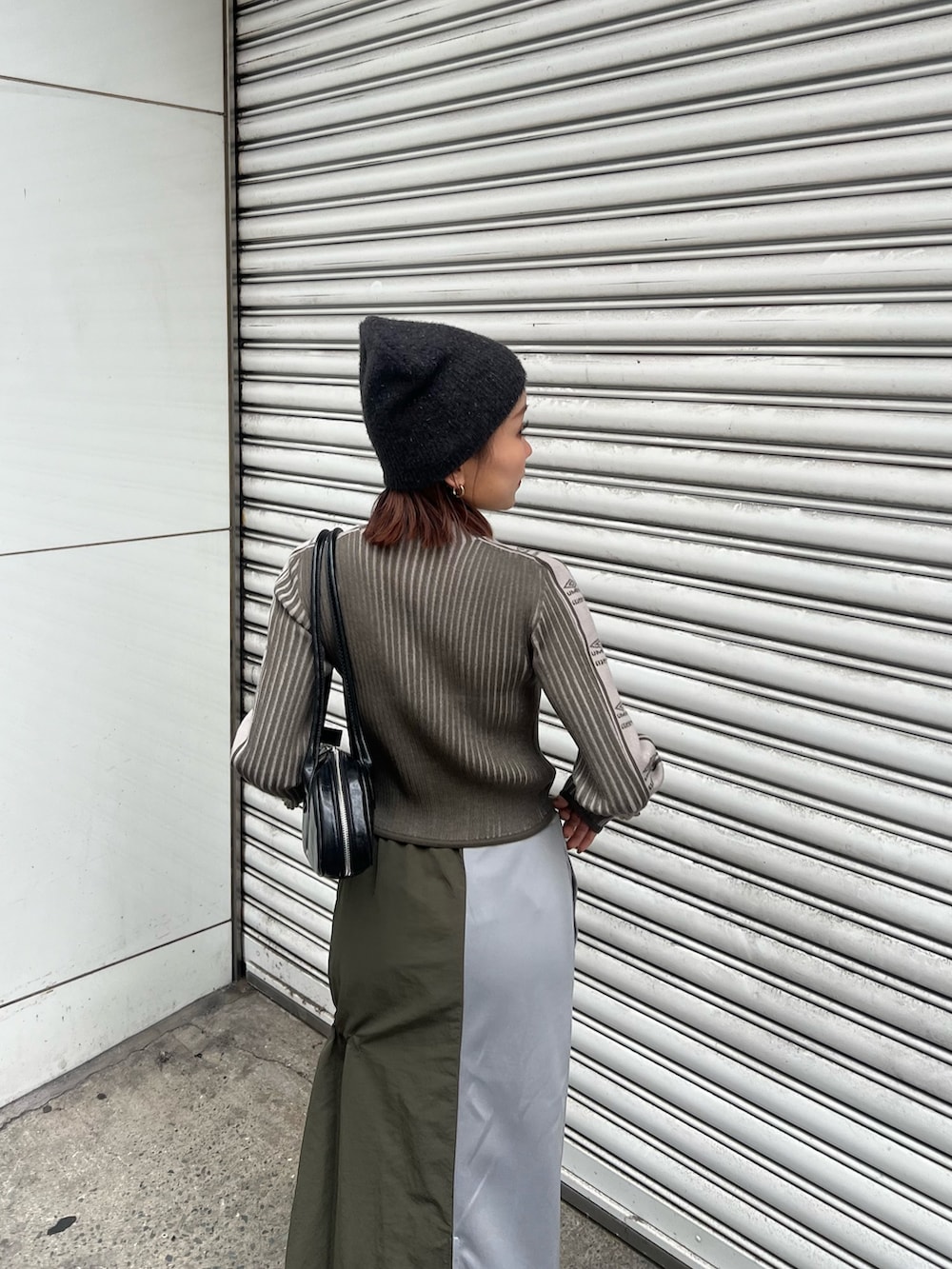 ブラック系のブーツ、グリーン系のニット/セーター、グリーン系のスカートを着用したレディースの秋コーディネートの6枚目の写真