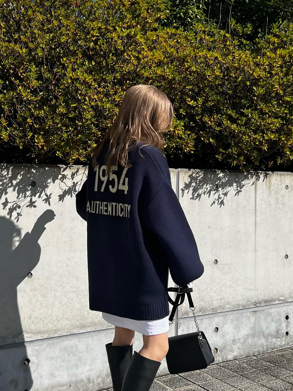 ブラック系のブーツ、ブラック系のショルダーバッグ、ホワイト系のTシャツ/カットソーを着用したレディースの秋コーディネートの6枚目の写真