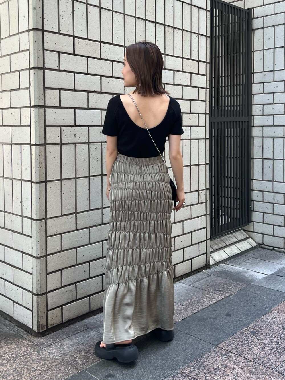 ブラック系のTシャツ/カットソー、グリーン系のスカート、ブラック系のショルダーバッグを着用したレディースの夏コーディネートの3枚目の写真