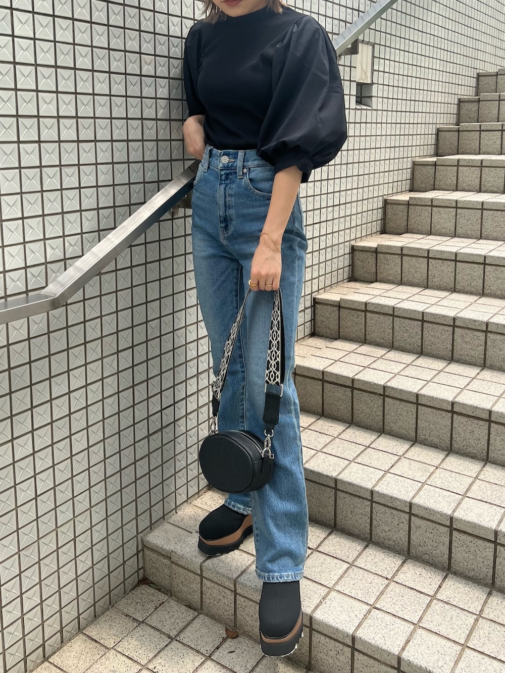 ブルー系のデニムパンツ、ブラック系のTシャツ/カットソー、ブラック系のショルダーバッグを着用したレディースの夏コーディネートの6枚目の写真