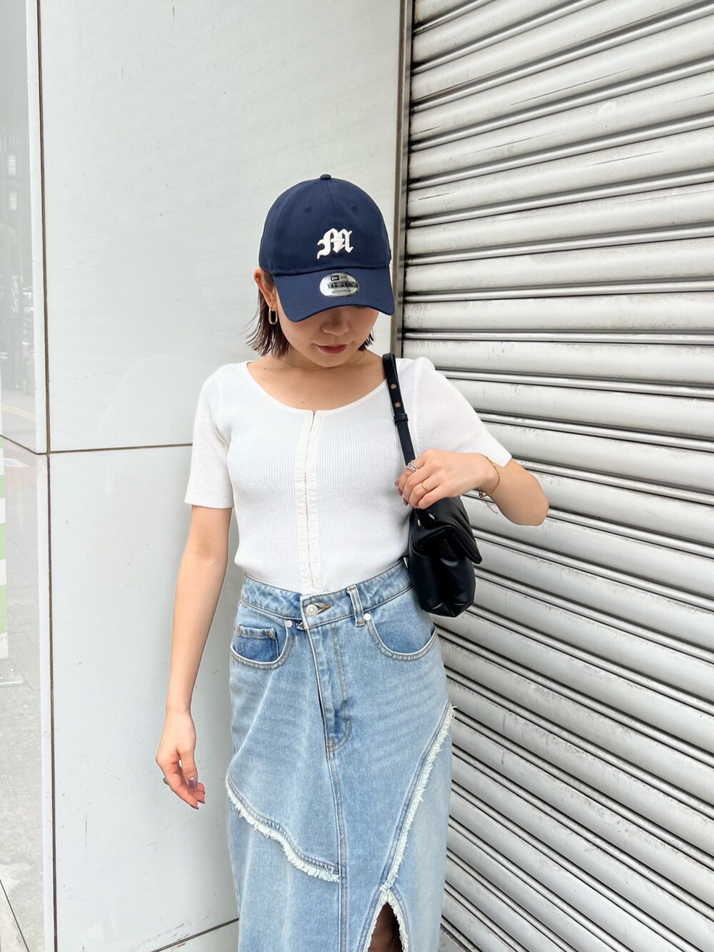 ホワイト系のニット/セーター、ブルー系のデニムスカート、ブラック系のハンドバッグを着用したレディースの夏コーディネートの5枚目の写真