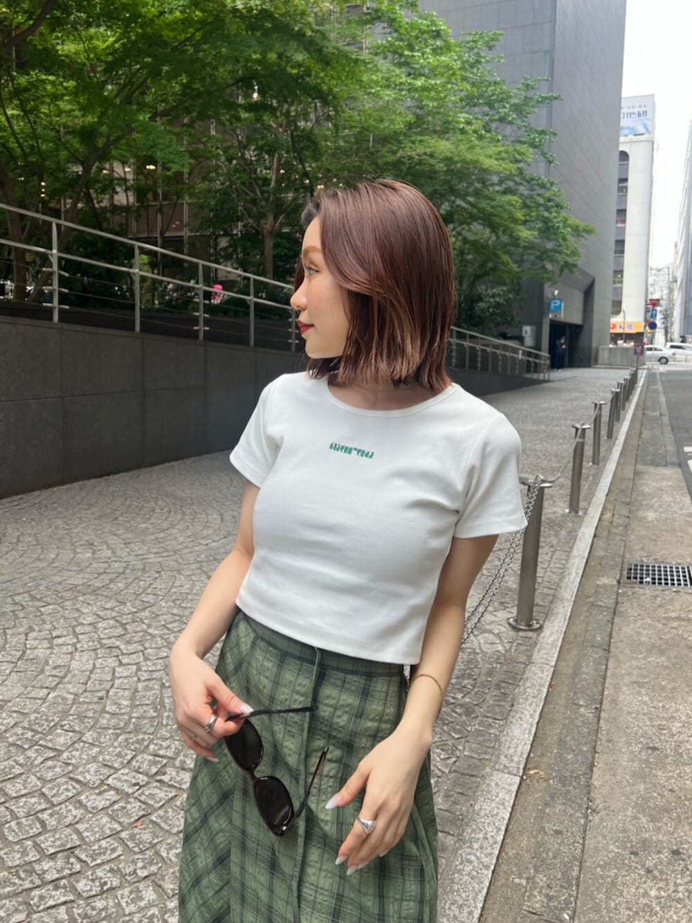 ブラック系のサンダル、ホワイト系のTシャツ/カットソー、グリーン系のスカートを着用したレディースの春コーディネートの5枚目の写真