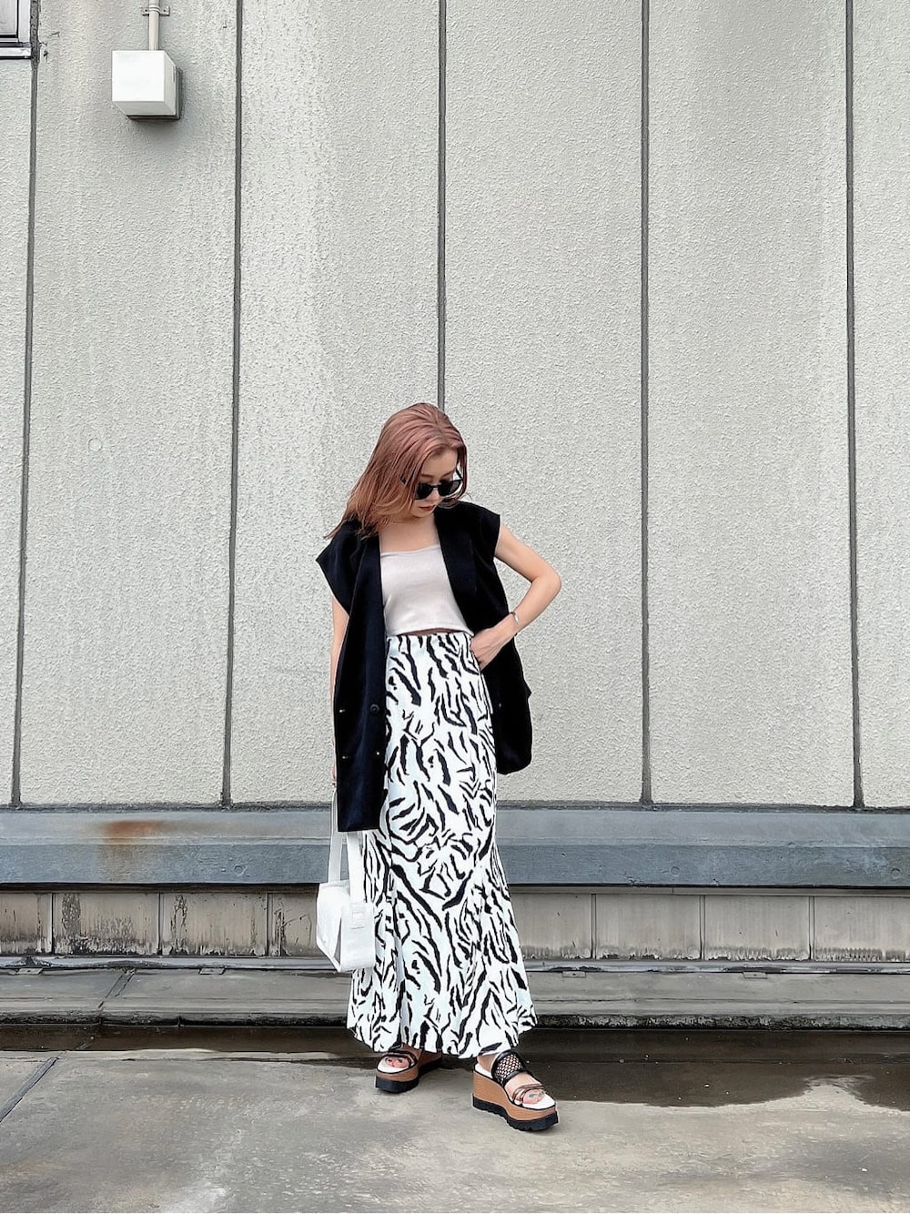 その他のサンダル、ブラック系のベスト、ホワイト系のハンドバッグを着用したレディースの夏コーディネートの7枚目の写真
