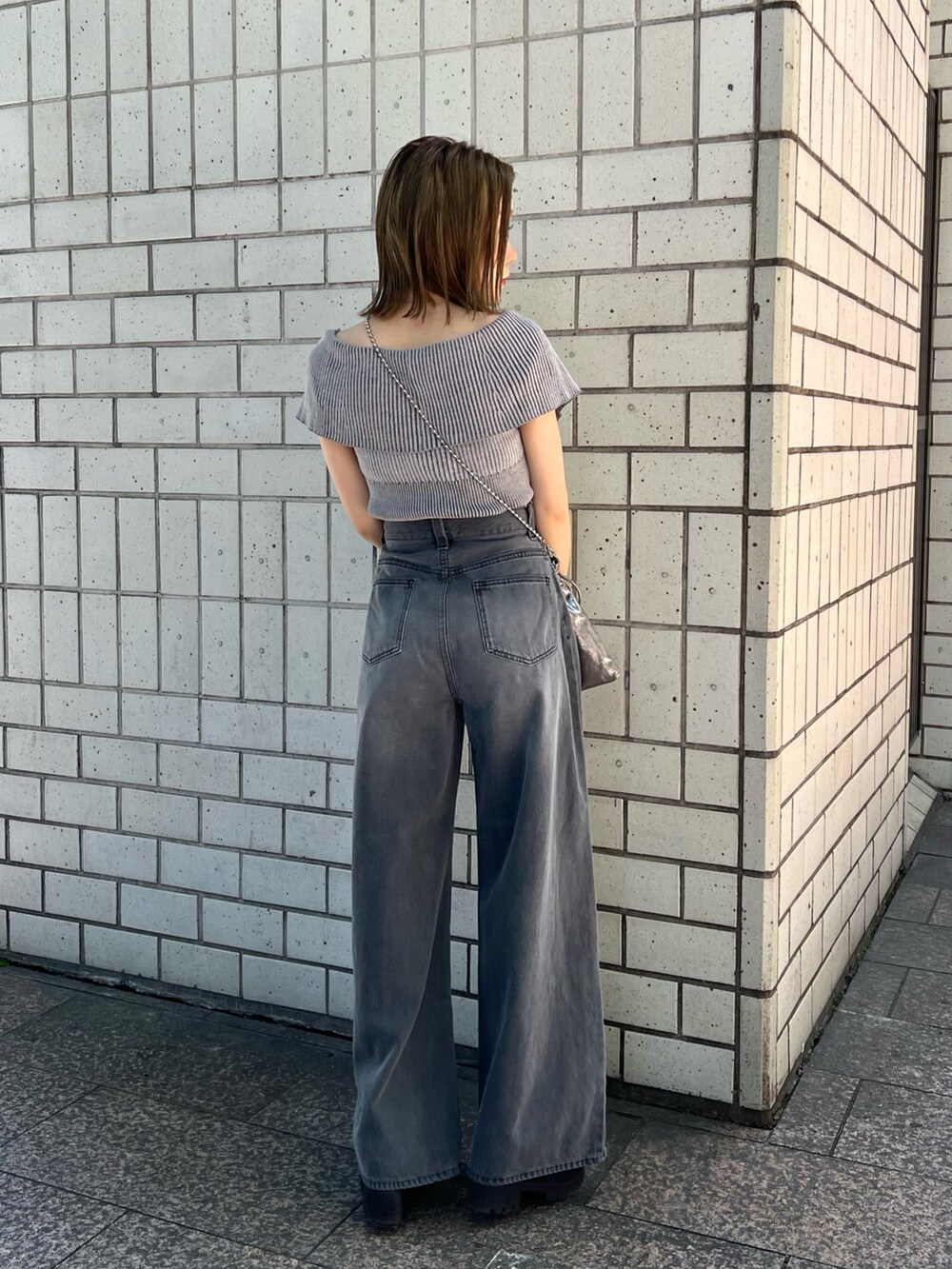 グレー系のニット/セーター、ブラック系のデニムパンツ、ブラック系のサンダルを着用したレディースの春コーディネートの2枚目の写真