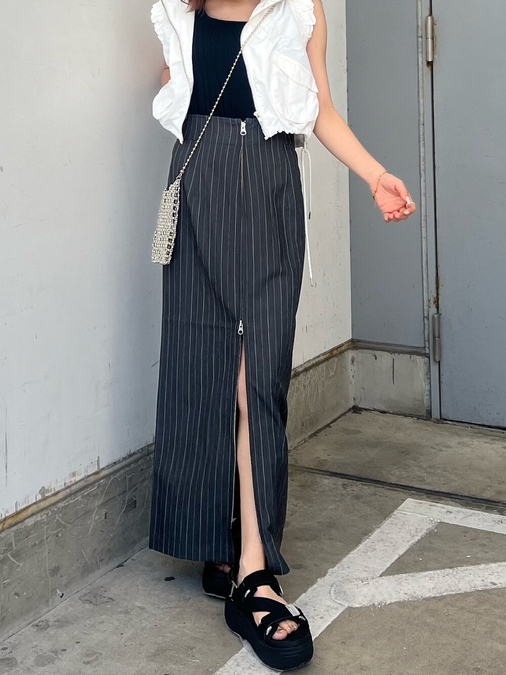 ホワイト系のベスト、ブラック系のタンクトップ、グレー系のスカートを着用したレディースの春コーディネートの5枚目の写真