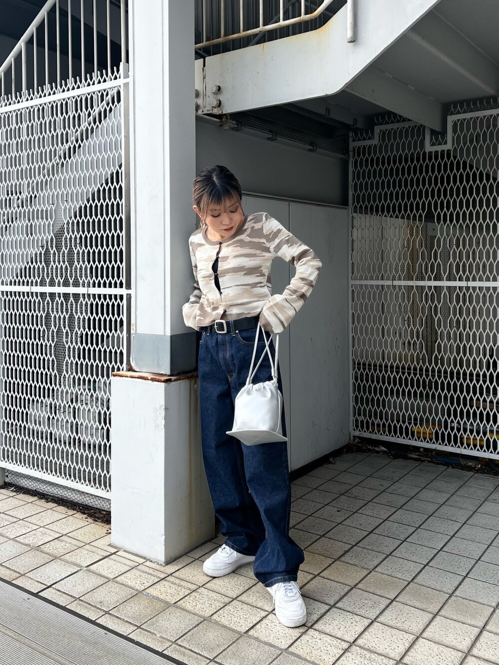 ブルー系のデニムパンツ、シルバー系のハンドバッグ、ベージュ系のカーディガン/ボレロを着用したレディースの冬コーディネートの3枚目の写真