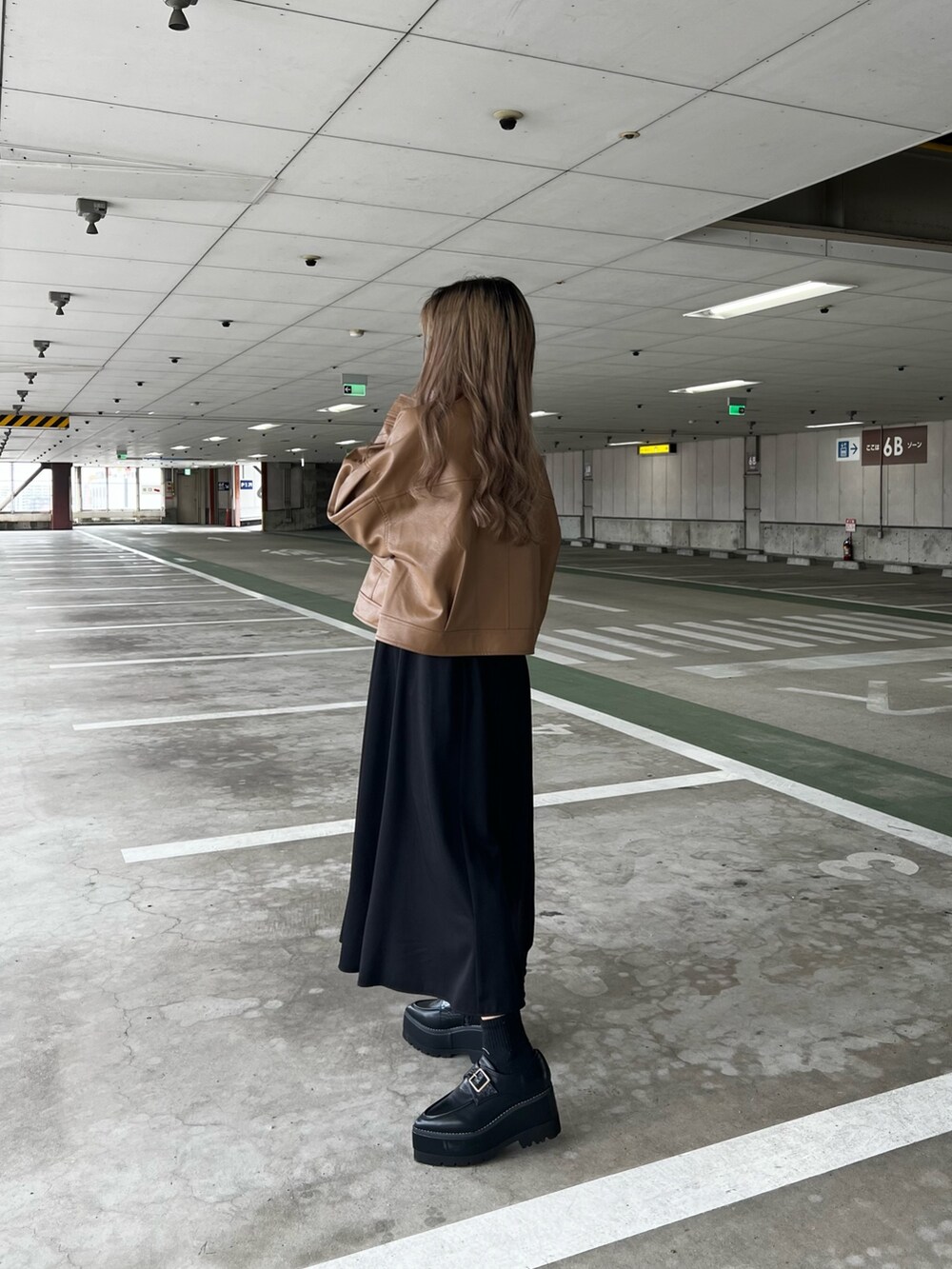 イエロー系のブルゾン、ブラック系のワンピース、ブラック系のハンドバッグを着用したレディースの冬コーディネートの3枚目の写真