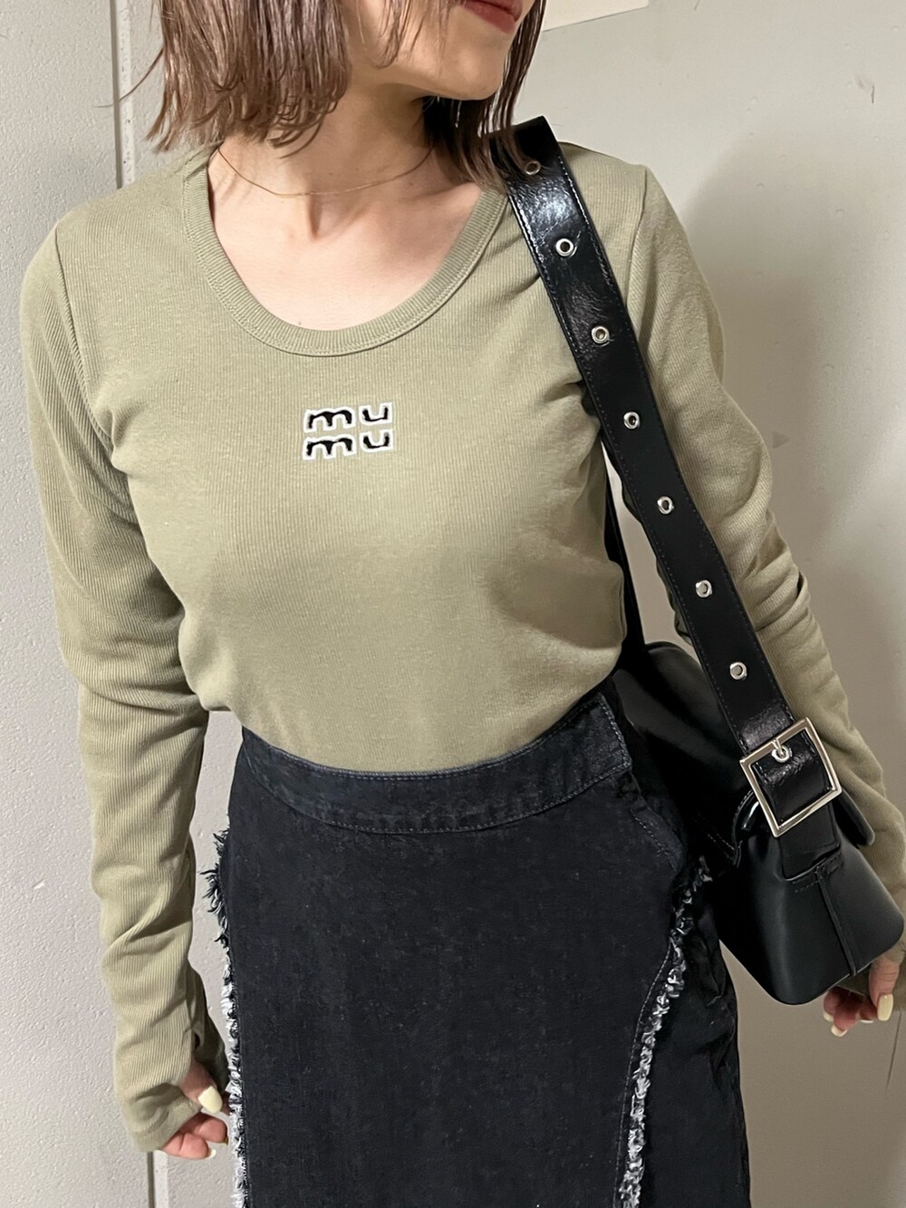 グリーン系のTシャツ/カットソー、ブラック系のデニムスカート、ブラック系のブーツを着用したレディースの冬コーディネートの7枚目の写真