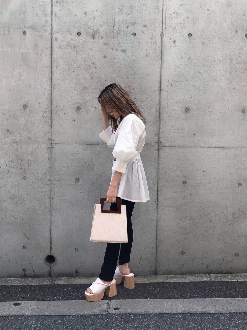 ホワイト系のサンダル、ブラック系のデニムパンツ、ホワイト系のハンドバッグを着用したレディースの春コーディネートの3枚目の写真